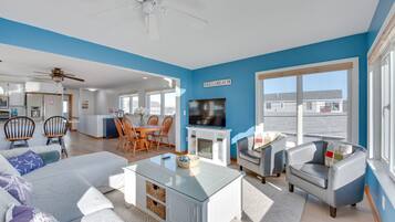 Un salon spacieux avec un mur d’accent bleu, une cheminée, un téléviseur et un coin repas doté de meubles en bois.