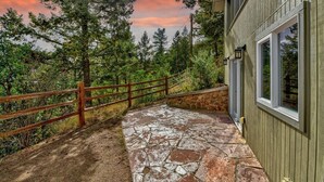 A stone pathway leading to a wooden building with a stone wall and a wooden fence. - Raven's Nest | Modern Forest Sanctuary (Cascade)