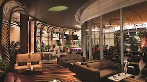 Un hall amplio con muebles modernos, ventanas grandes y diversas zonas de estar.
