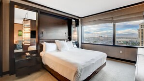 Habitación de hotel moderna con una cama grande, una mesita de noche, un espejo y vistas a la ciudad a través de amplias ventanas.