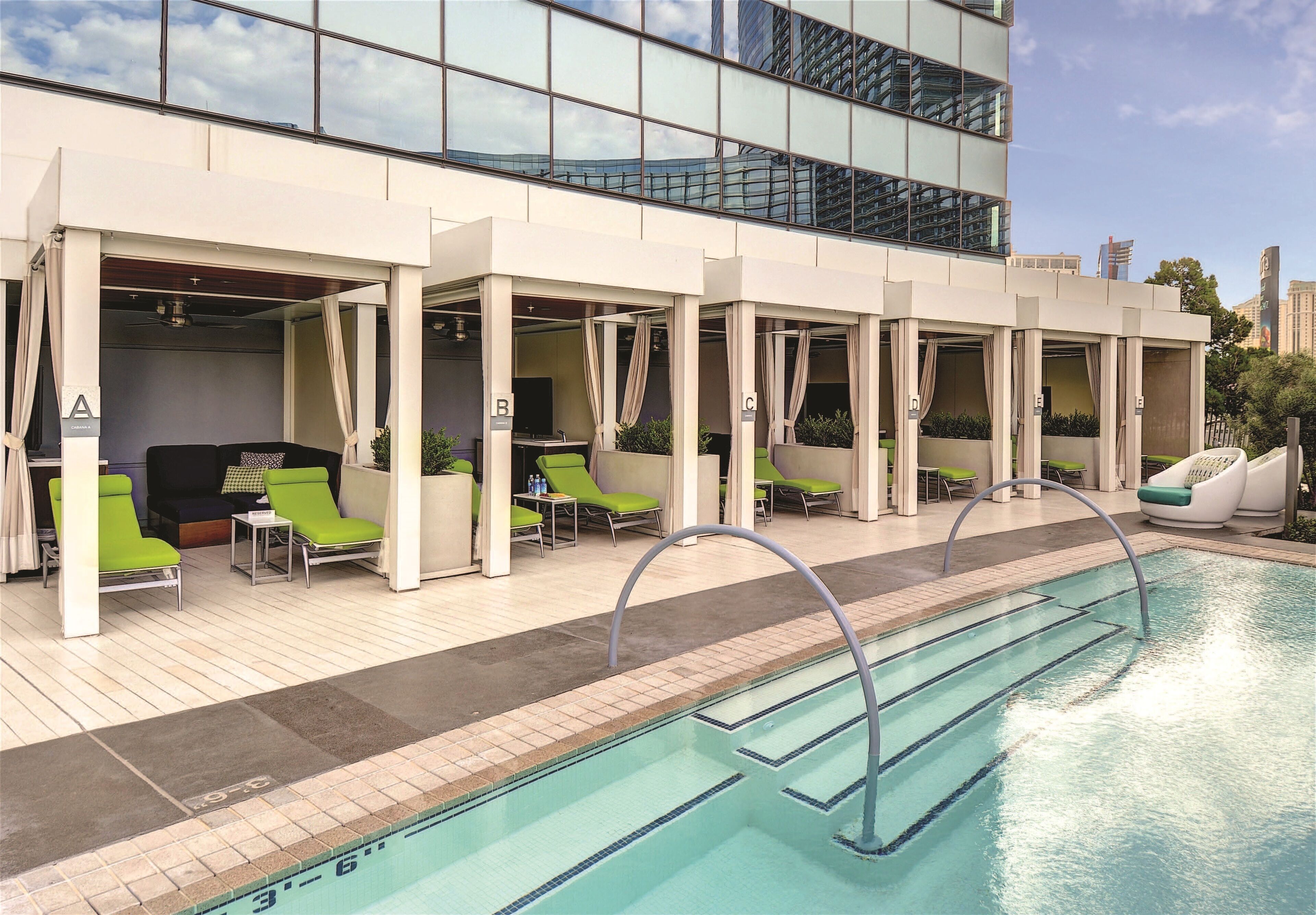 A rooftop pool area with lounge chairs and a view of the city skyline.