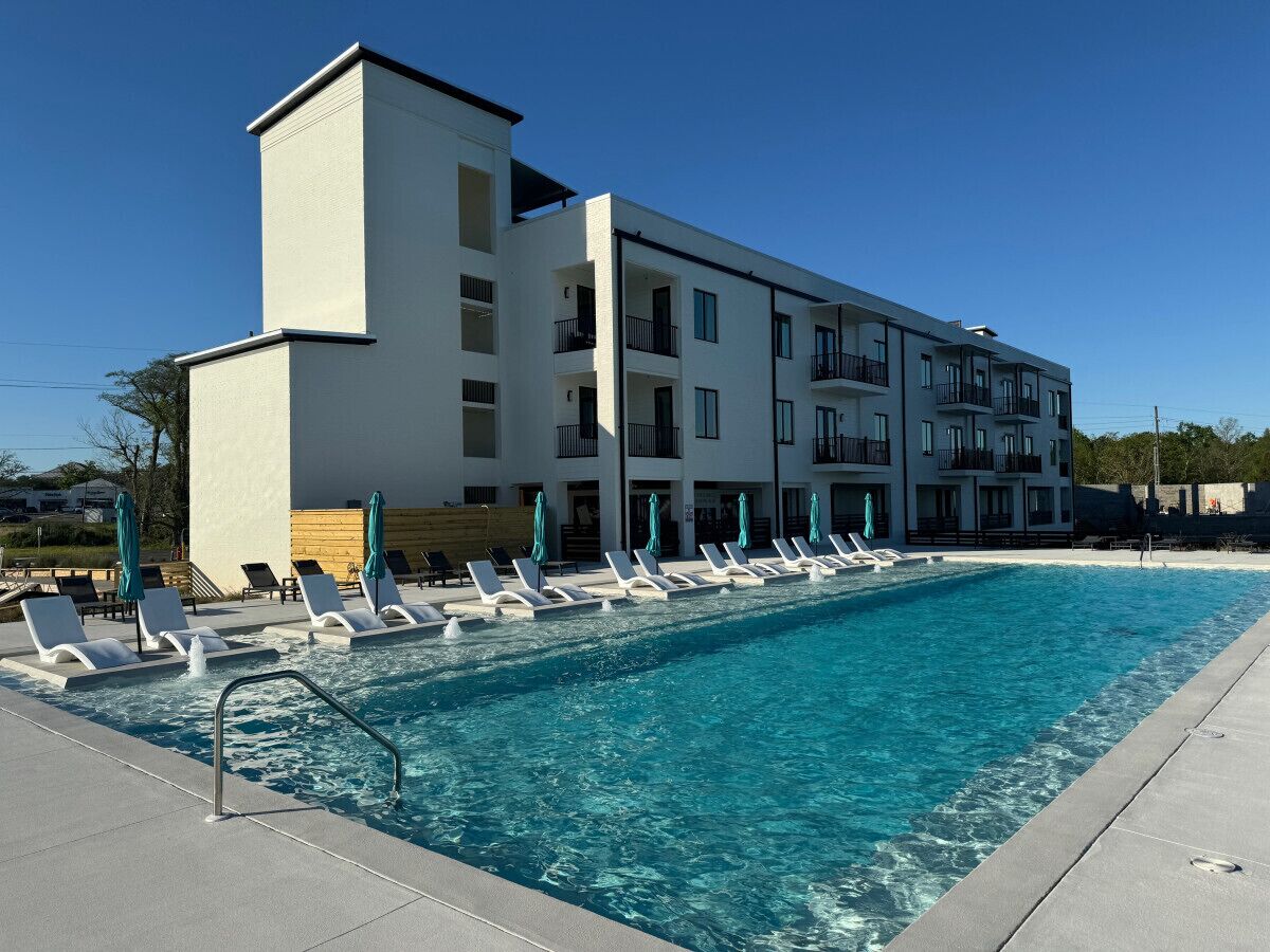 Un hôtel moderne doté d’une piscine, de nombreux balcons et de chaises longues.
