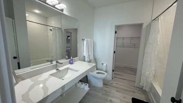 Een moderne badkamer met een witte wastafel, spiegel en toilet.