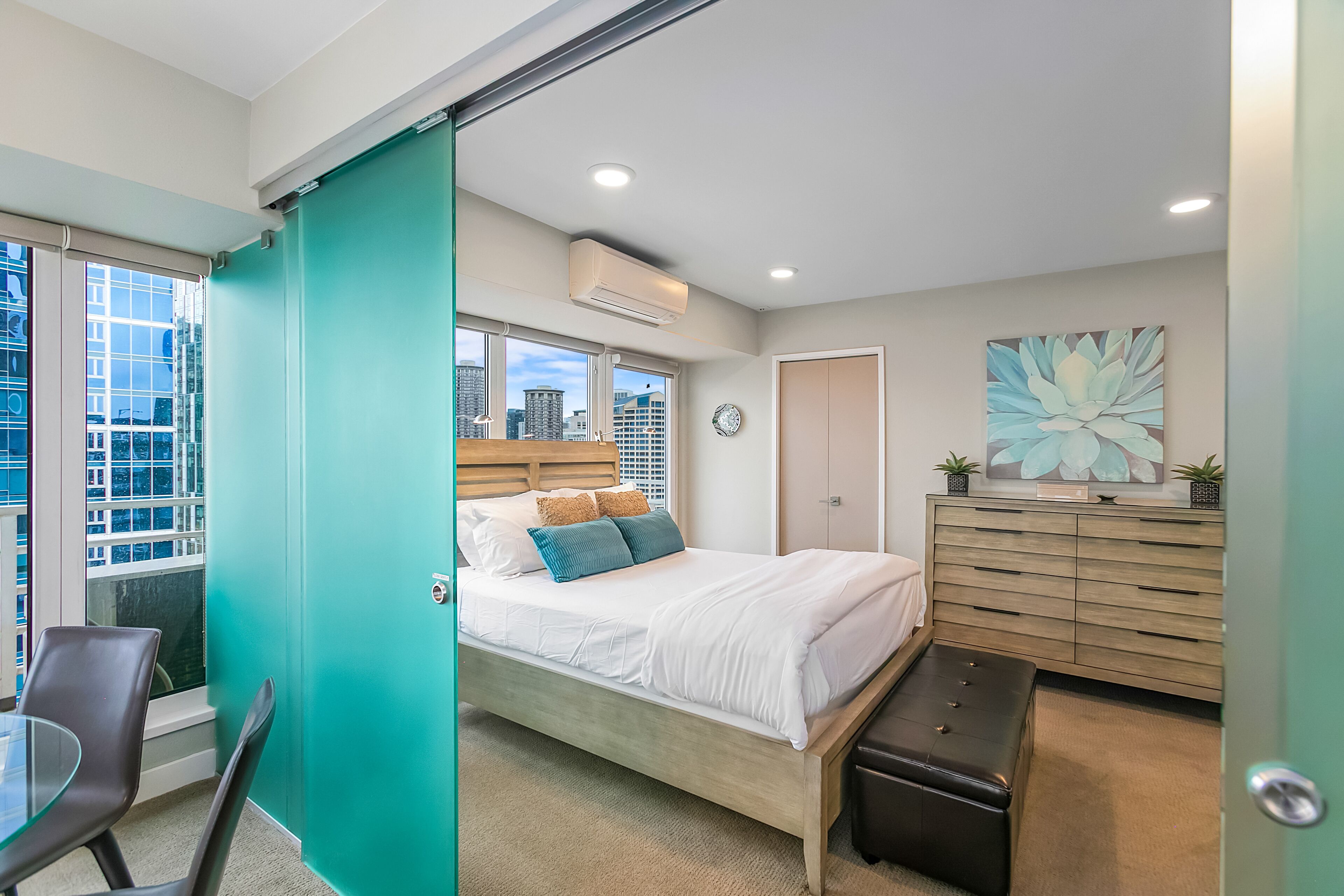 Une chambre moderne avec un lit, un bureau et une vue sur la ville.