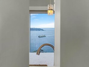A view from a window overlooking a body of water with a cruise ship in the distance and a landmass with buildings. - NewMark Towers Water Wheel Sea Views (Seattle)