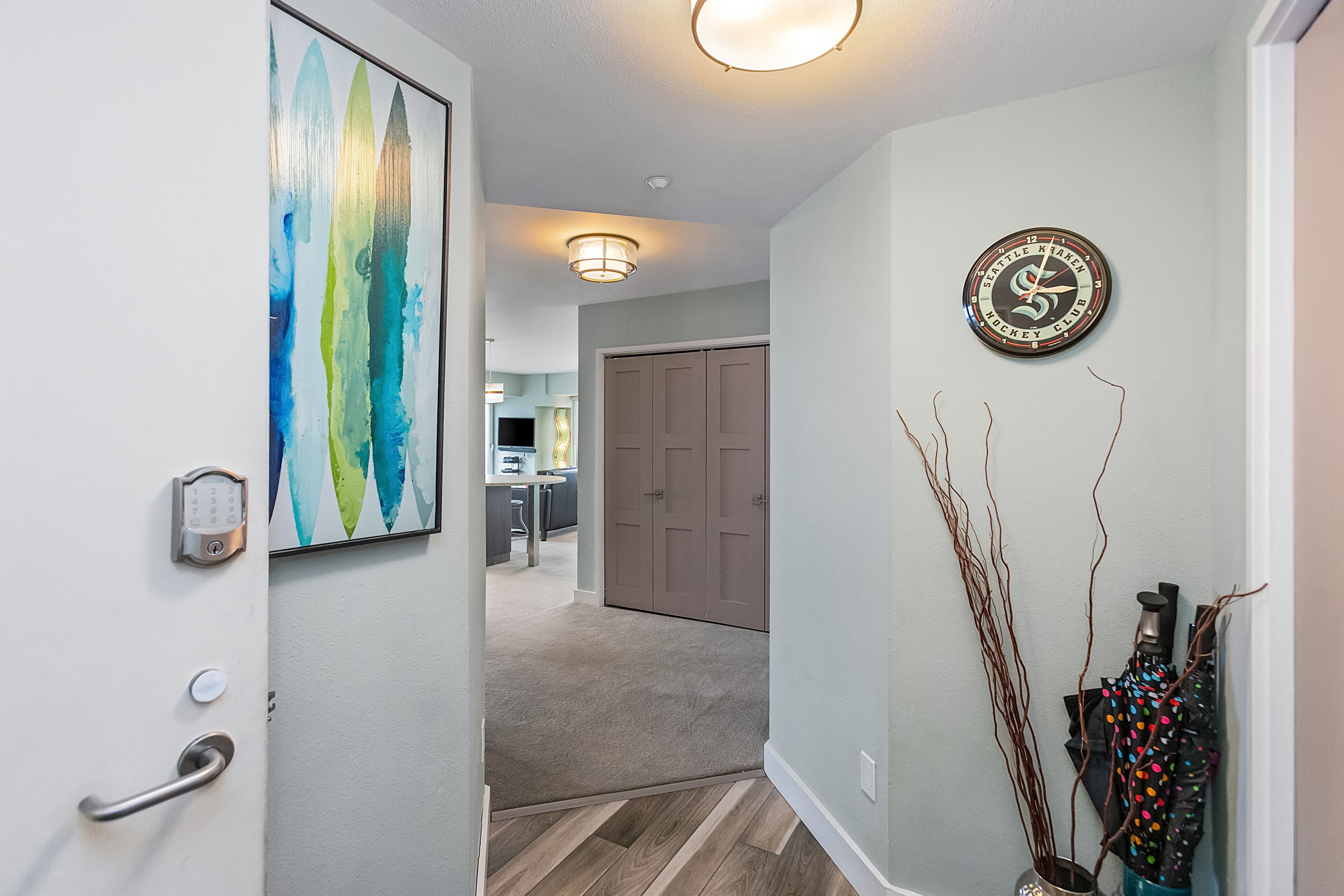 A hallway with a door, a wall clock, and a doorbell.