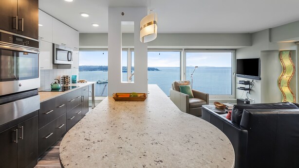 A modern kitchen with a large island, built-in appliances, and a view of the sea. - NewMark Towers Water Wheel Sea Views (Seattle)