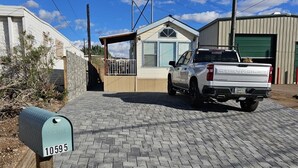 A residential driveway with a white pickup truck parked in front of a house.