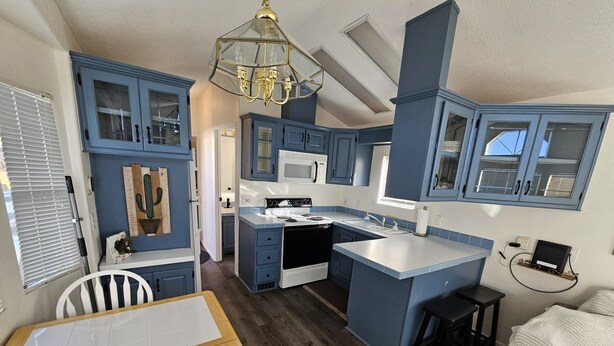 A compact kitchen with blue cabinets, a white countertop, and a central island.