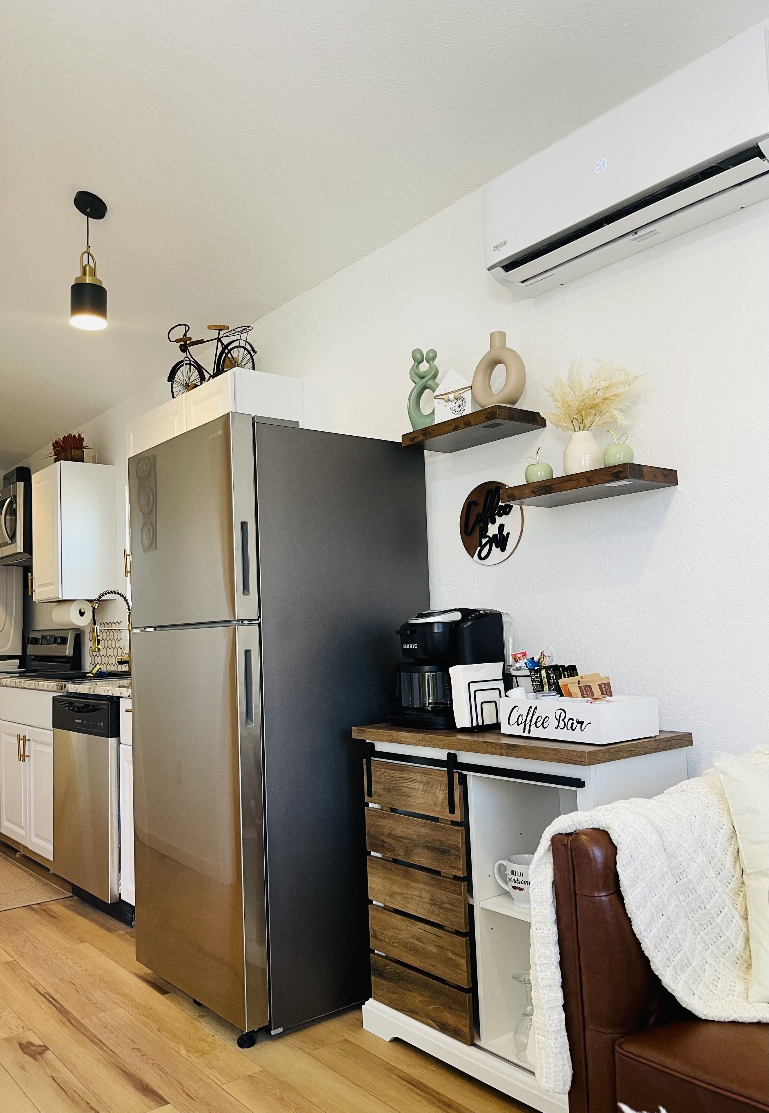 Een moderne keuken met een roestvrijstalen koelkast, een koffiebar en een wandairconditioner.