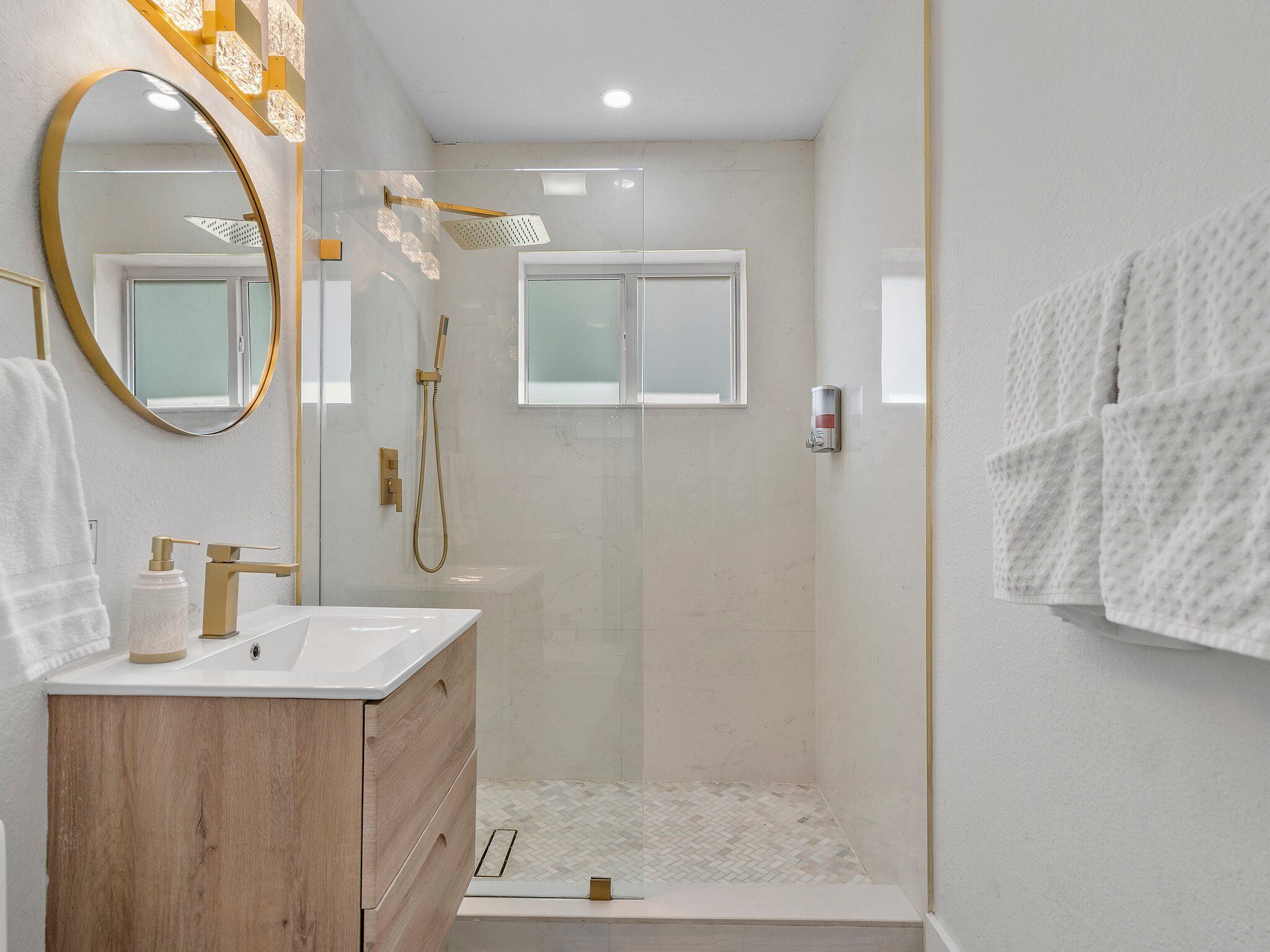 A modern bathroom with a wooden vanity, a large mirror, a shower with a glass door, and a towel rack.