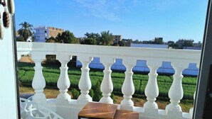 A balcony with white balustrades, a wooden table, and two white chairs.