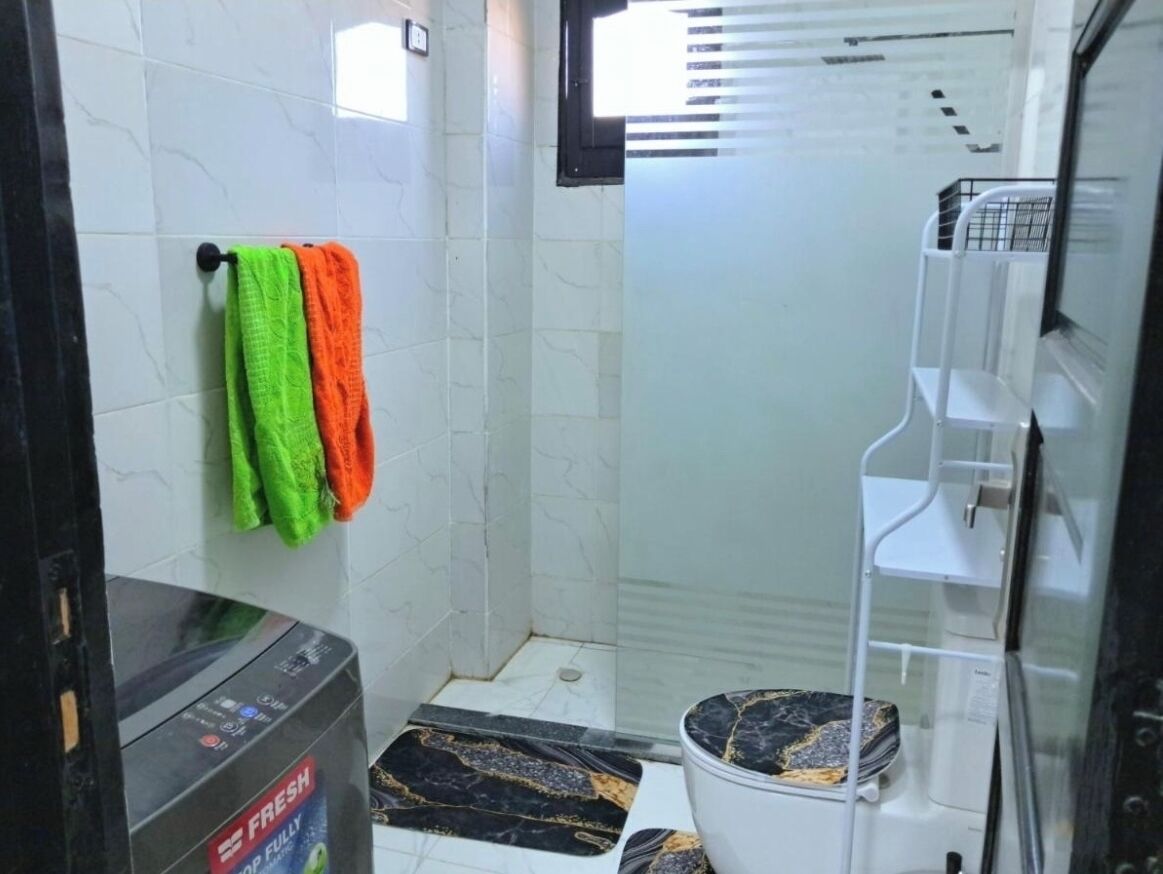 Ein Badezimmer mit Toilette, Dusche und Waschbecken. Handtücher hängen an der Wand.
