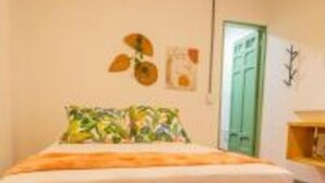 Een slaapkamer met een bed, een groene deur en een plant aan de muur.