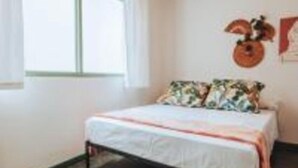 Een slaapkamer met een bed, een raam en een wanddecoratie.