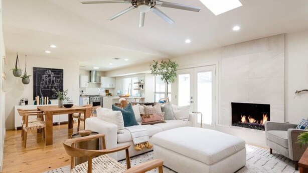 A spacious living room with a white sofa, a wooden dining table, and a fireplace. - Fireplace, Fire Pit, Turf Backyard | Central ATX (Austin)