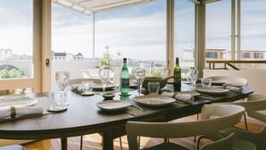 Comedor con una mesa dispuesta para cuatro personas, ventanas amplias y vista panorámica de la ciudad.