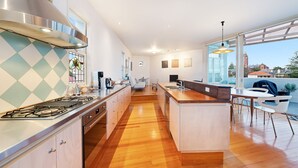 Una cocina moderna con una isla central, electrodomésticos de acero inoxidable y un amplio ventanal con vistas a la ciudad.