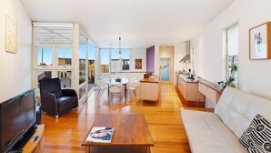 Un amplio salón con una mesa de centro de madera, un sofá, un televisor y una mesa de comedor con sillas.