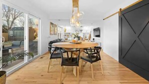 Et moderne spiseområde med et træbord, sorte stole og en hængende lampe.