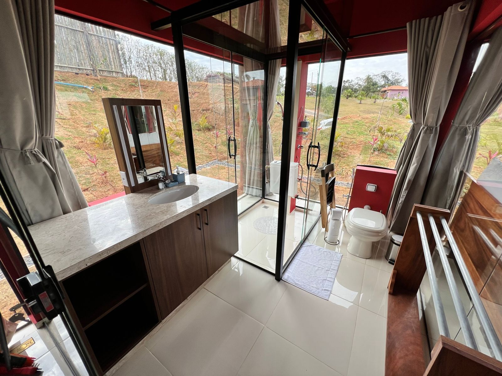 A modern bathroom with a large window, a sink, and a toilet.