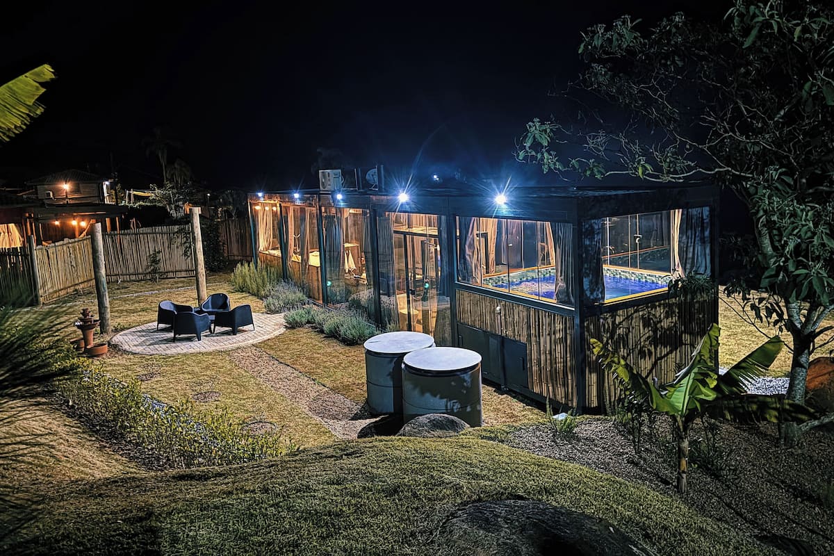 A well-lit outdoor area with a pool, covered seating, and a wooden structure.