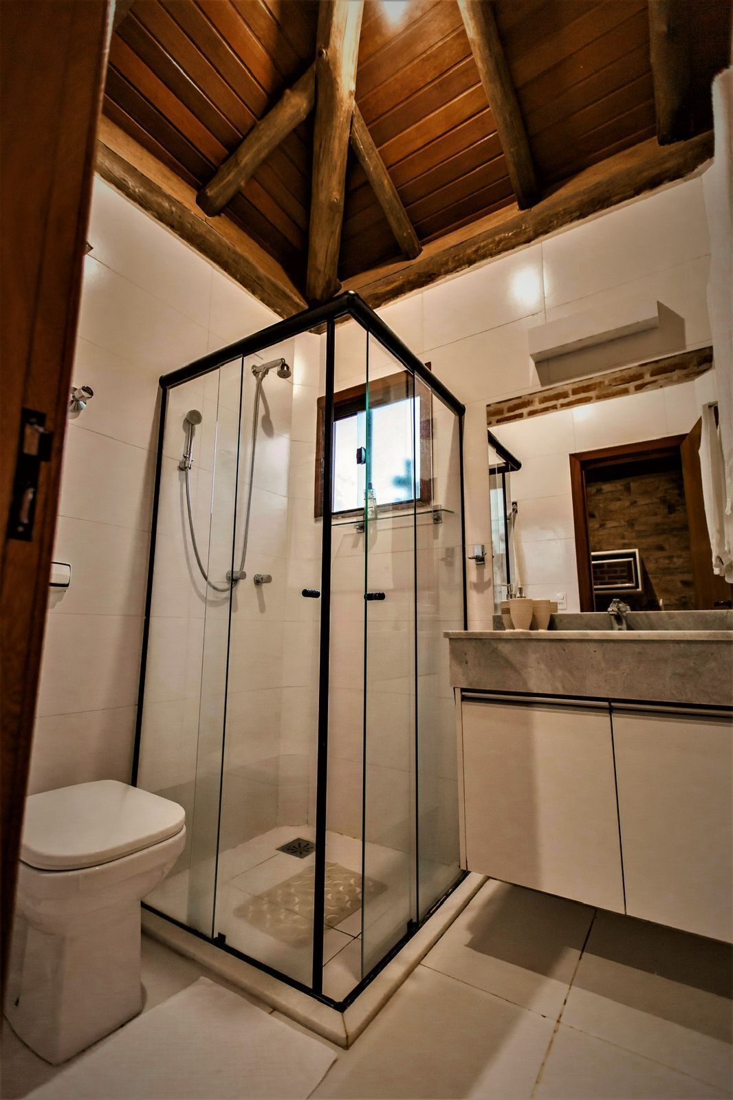 A modern bathroom with a glass-enclosed shower, a toilet, and a vanity with a mirror.