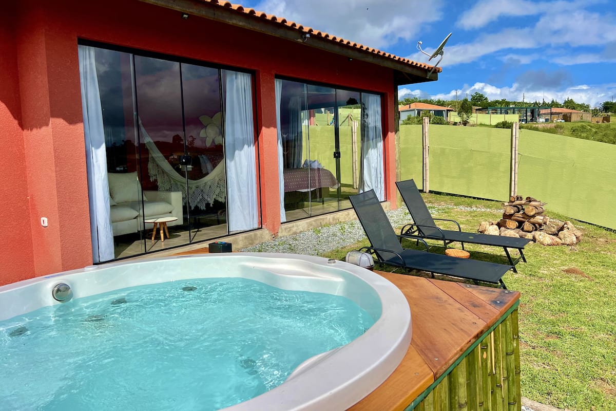 A modern house with a hot tub, outdoor seating, and a view of a golf course.