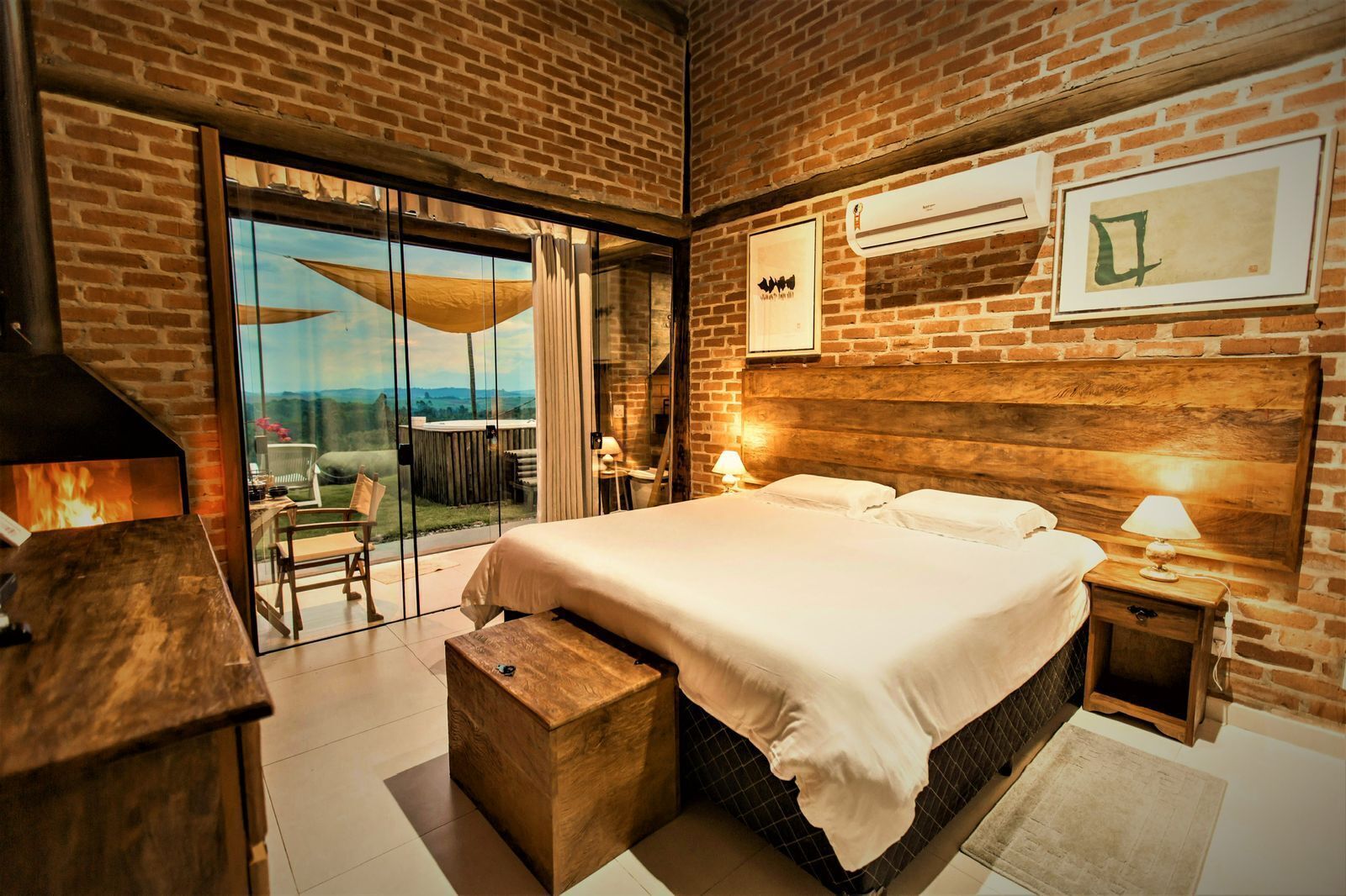A modern bedroom with a large bed, a wooden headboard, a glass door leading to a balcony, and a fireplace.