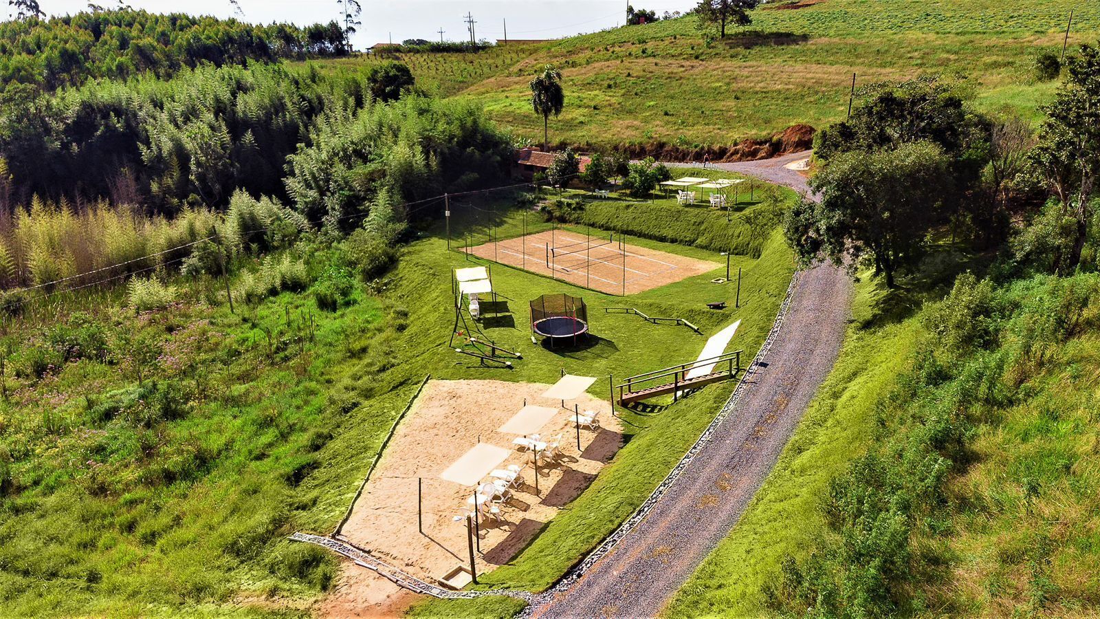 Luchtbeeld van een pand met een tennisbaan, een zwembad en een overdekt zitgedeelte.
