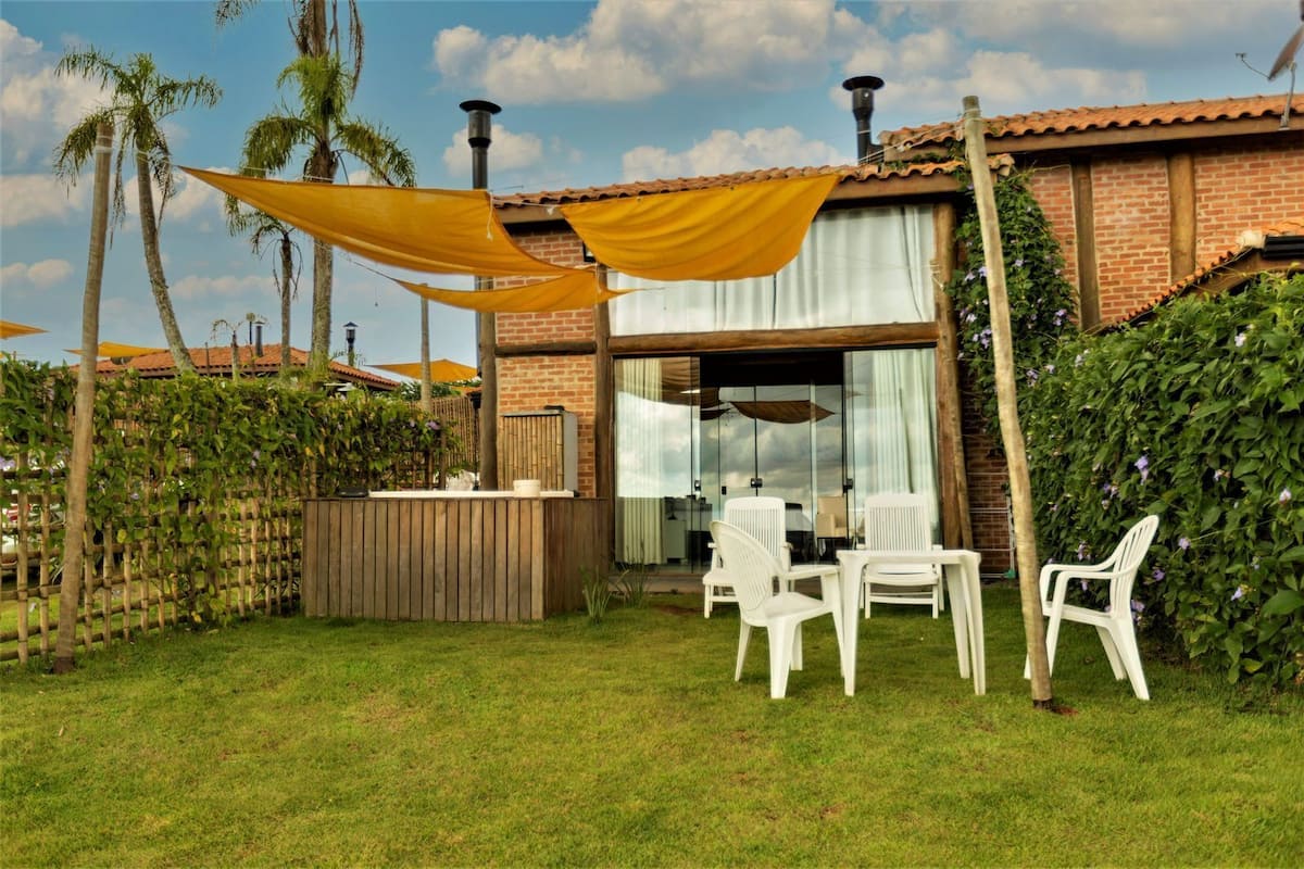 A patio area with a wooden fence, a brick building, and a table with chairs.