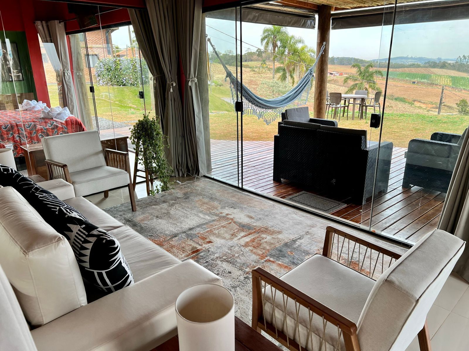 A spacious living area with a large window, a hammock, and a TV.