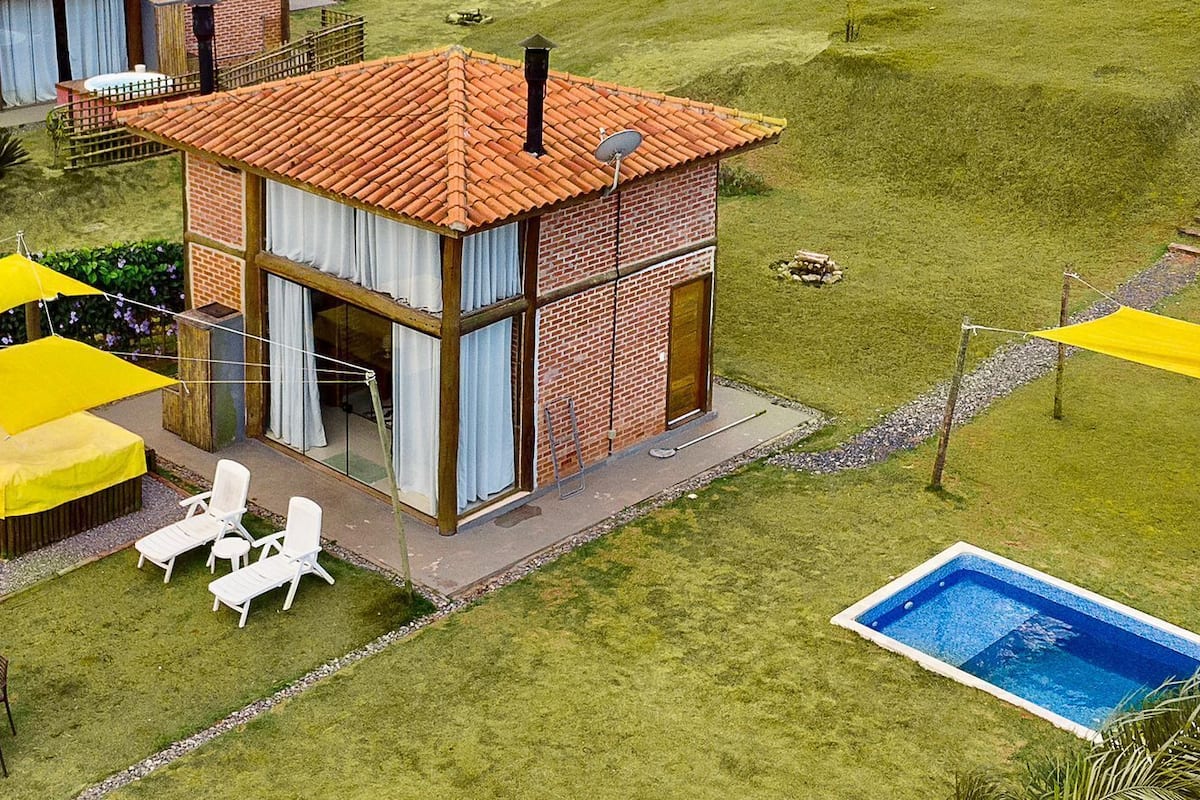 A modern two-story house with a brick exterior, a tiled roof, and a small swimming pool.