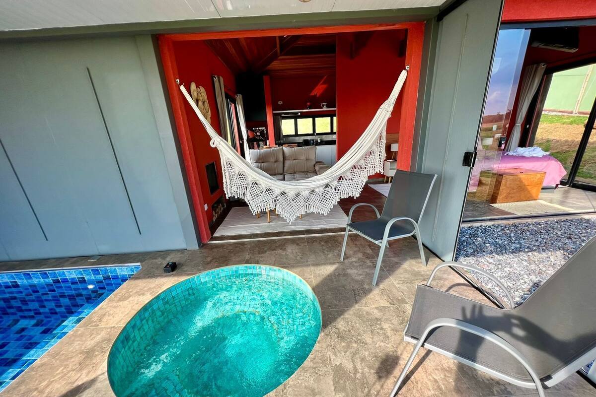 A pool area with a hot tub, a hammock, and outdoor seating.