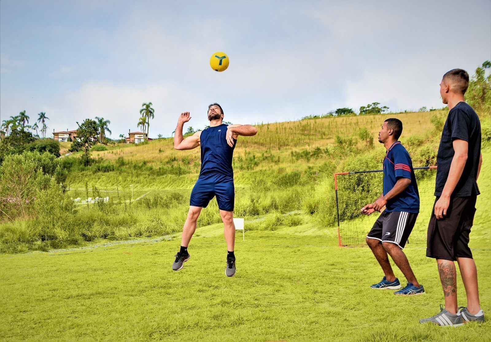 Un grupo de personas jugando un juego al aire libre en un campo cubierto de césped, con un arco de fútbol.