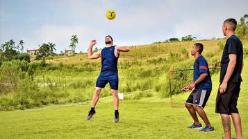 Un grupo de personas jugando un juego al aire libre en un campo cubierto de césped, con un arco de fútbol.