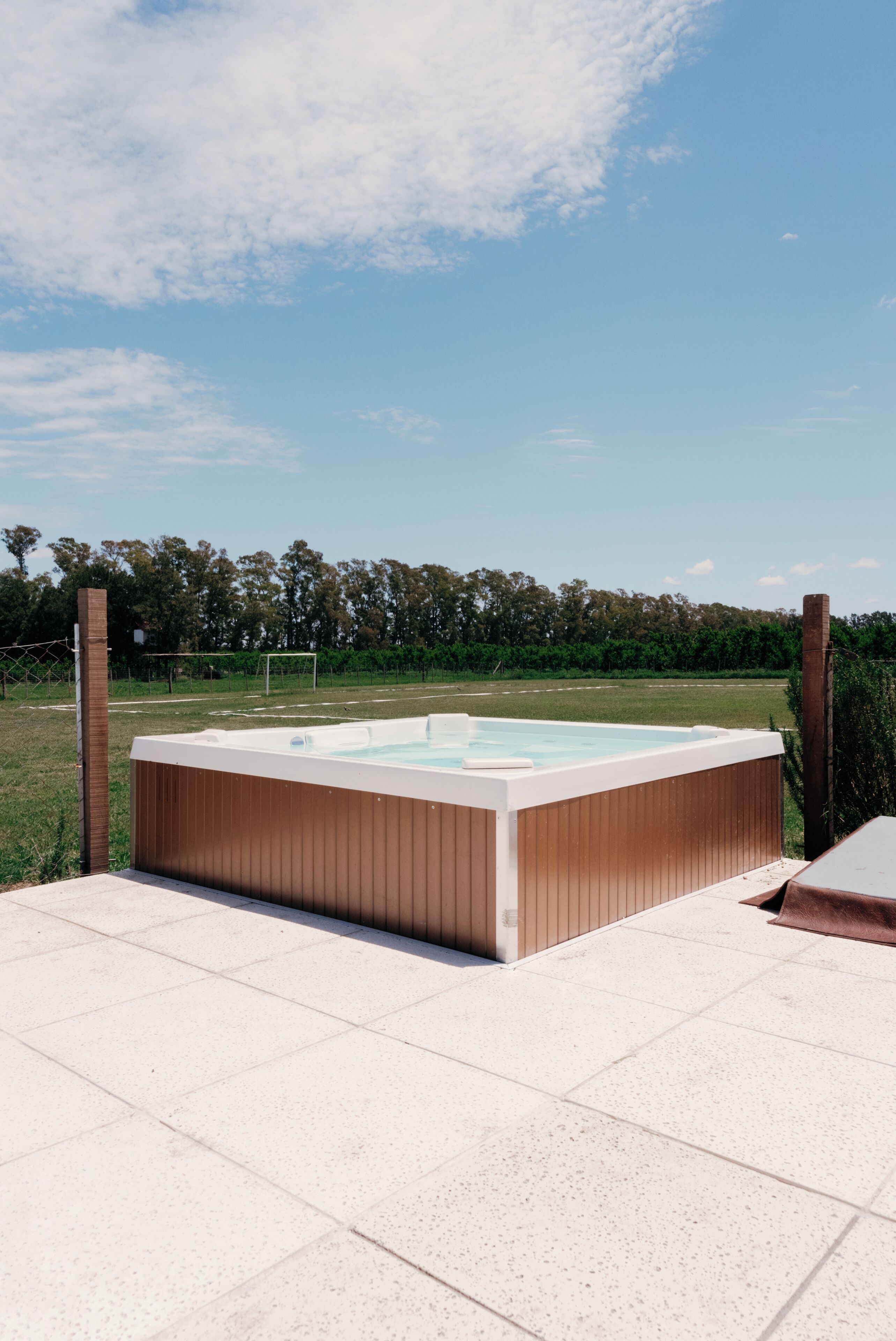 Ein rechteckiges Whirlpool mit Holzverkleidung, umgeben von einer gefliesten Terrasse.