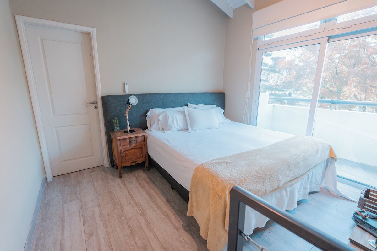 Ein Schlafzimmer mit Bett, Nachttisch und Fenster mit Blick.