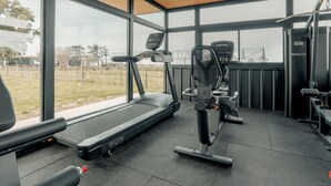 Un gimnasio con caminadora, bicicleta estática y máquinas de pesas.