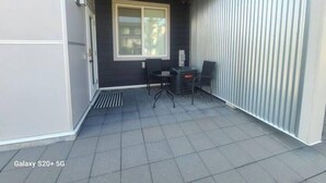 A covered patio area with a table and chairs, a window, and a door.