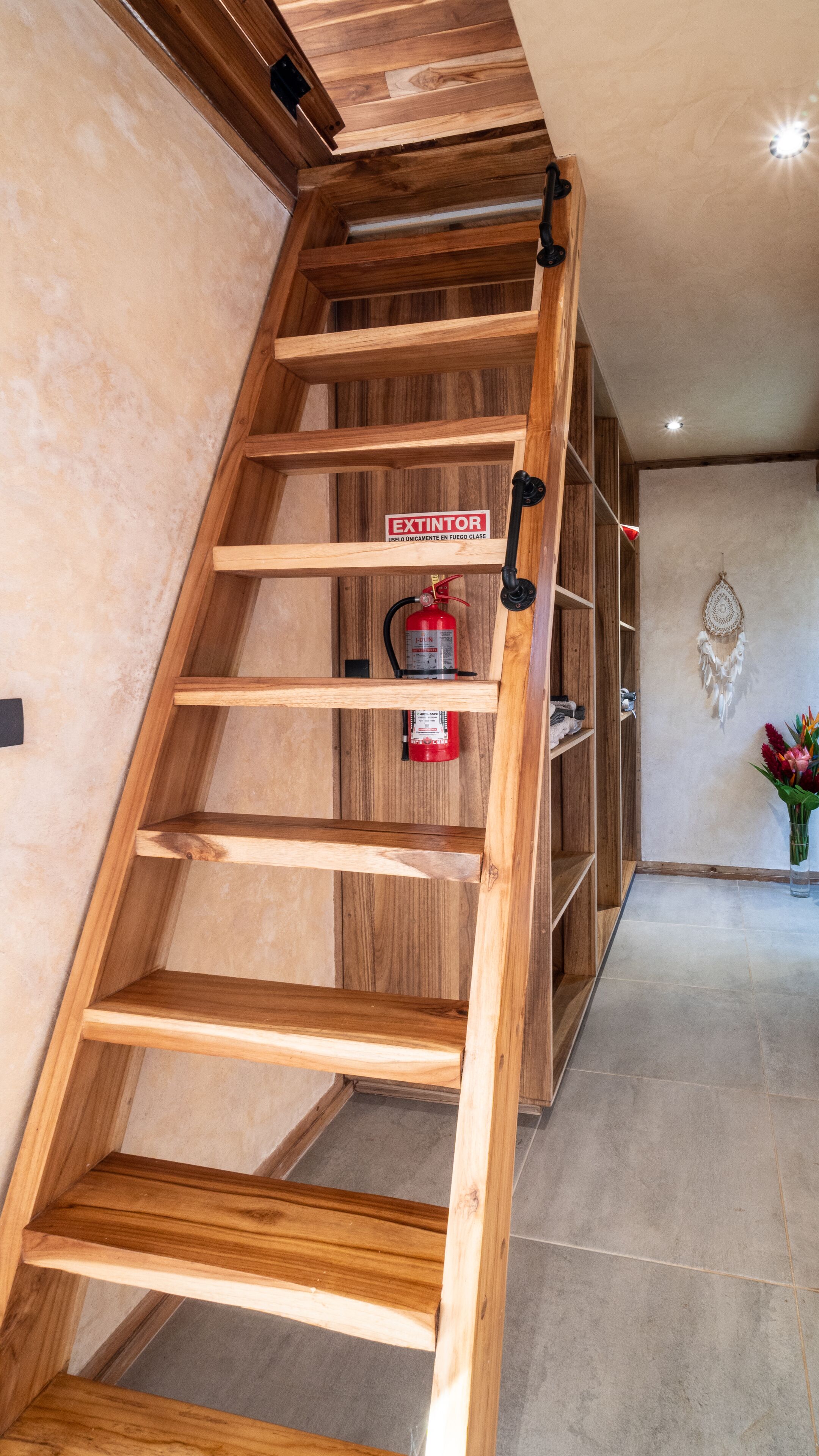 Eine Holztretppe mit an der Wand befestigtem Feuerlöscher.