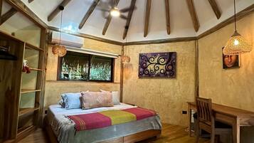A cozy bedroom with a sloped ceiling, a bed with a colorful blanket, a wooden desk, and a chair.