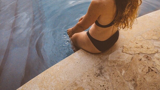 A person sitting by a pool with a mountainous landscape in the background. - Tierra Encantada Wellness Center (Nosara)