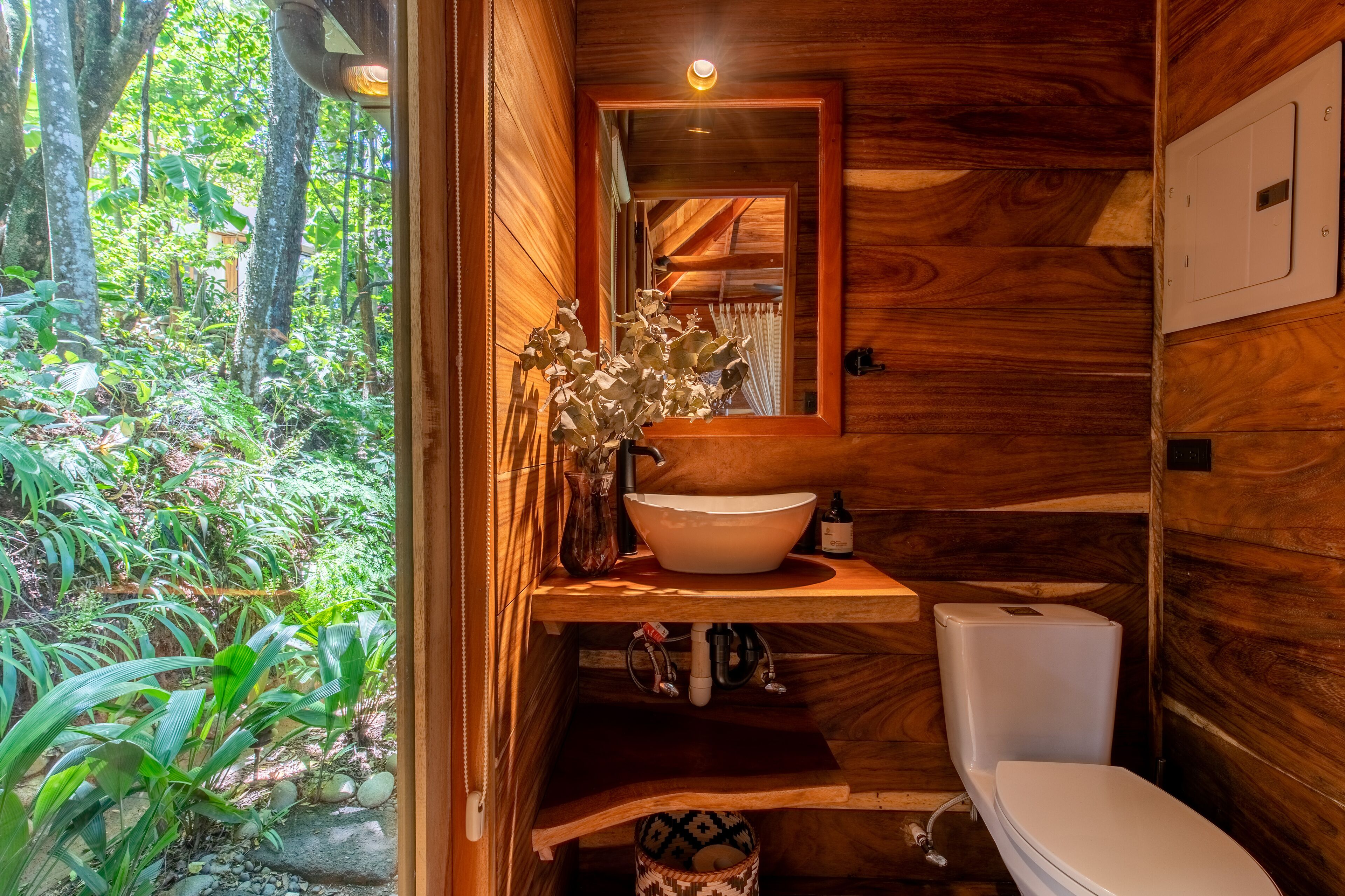 Ein Badezimmer aus Holz mit einem großen Waschbecken, Toilette und einem Spiegel.