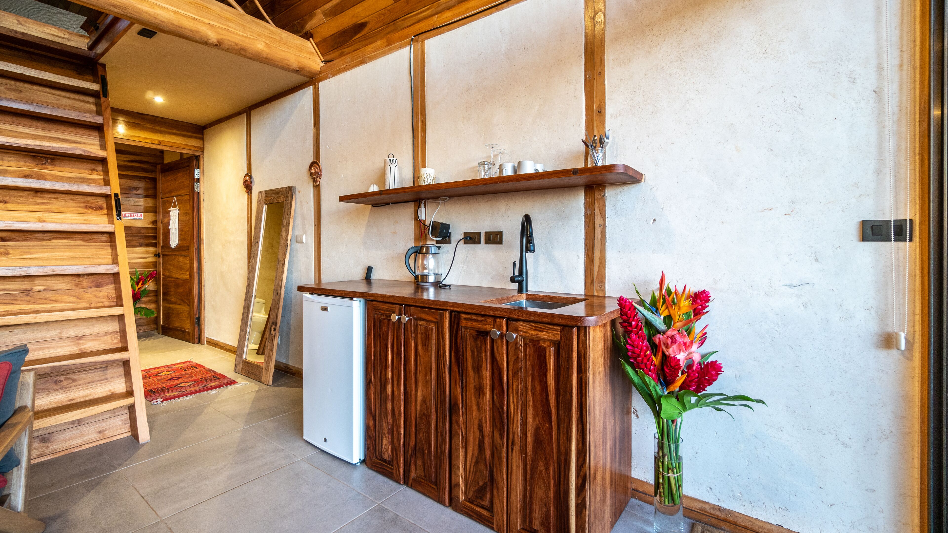 A kitchen with wooden cabinets, a white refrigerator, a coffee maker, and a vase with flowers.