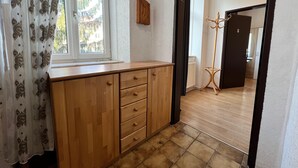 A room with a wooden cabinet, a window with patterned curtains, and a view of the outside. - EasyStay 3BR shared Apt. Near Meidling (Vienna)