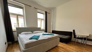 A modern bedroom with a large bed, a sofa, a small table, and a chair. - EasyStay 3BR shared Apt. Near Meidling (Vienna)