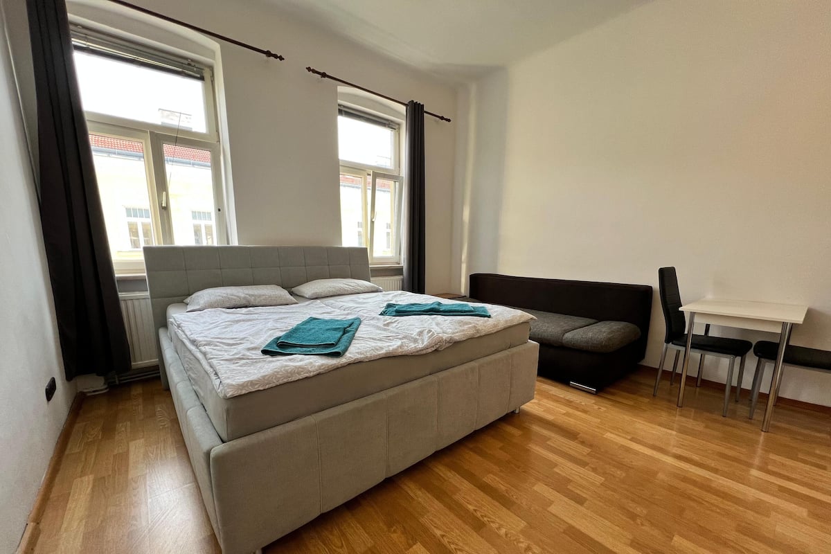 Quarto moderno com uma cama grande, um sofá, uma mesinha e uma cadeira.