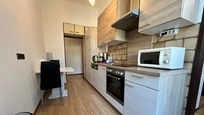 A compact kitchen with a microwave, oven, and wooden cabinets. - EasyStay 3BR shared Apt. Near Meidling (Vienna)