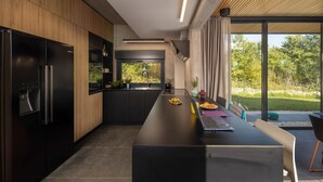 Una cocina moderna con una isla central, armarios negros y vistas al exterior.